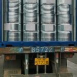 An open shipping container filled with neatly stacked metal drums, part of Eapearl Chem's delivery consignment.