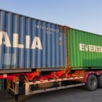 Shipping containers from Italia and Evergreen on a transport trailer, part of Eapearl Chem's delivery system.