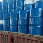 A worker standing atop a truck bed filled with neatly organized blue industrial barrels from Eapearl Chem.