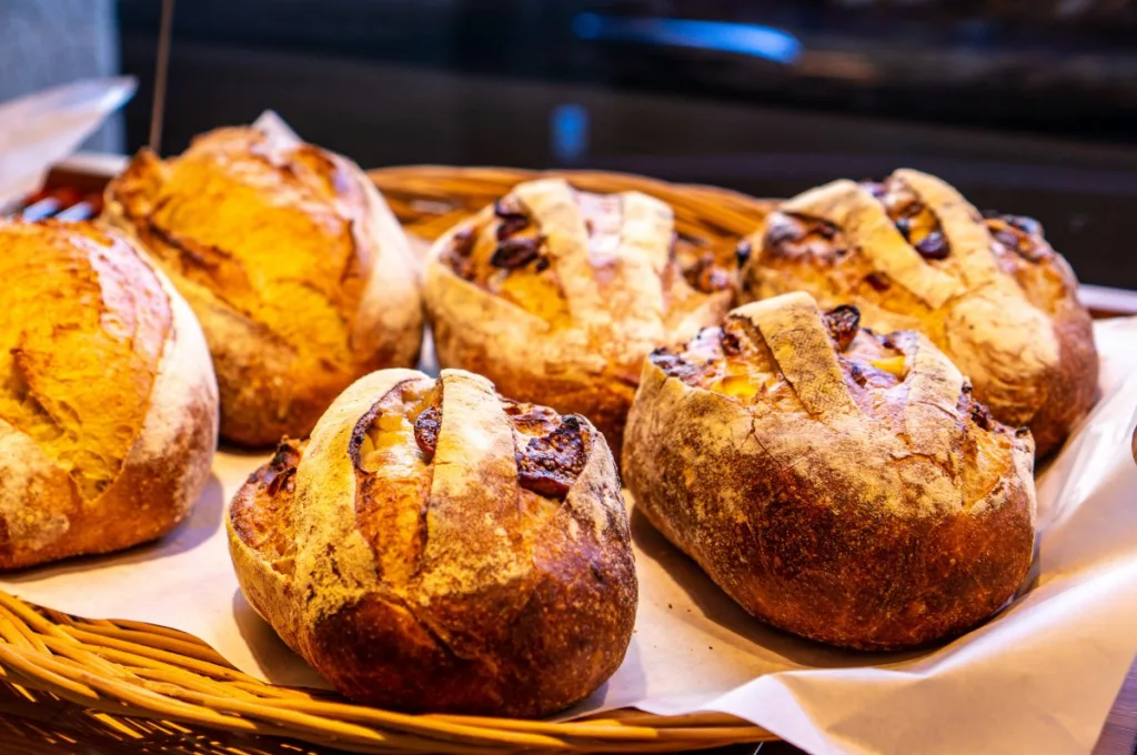 Freshly baked artisan breads in a basket, showcasing a variety of crusty loaves.