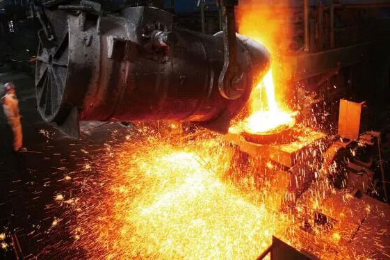 Furnace in an industrial metallurgy facility pouring molten metal with sparks, illustrating high-temperature metal processing.