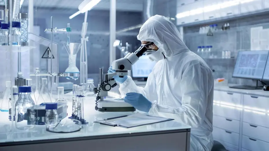 Scientist in a protective suit conducting research using a microscope in a high-tech laboratory.