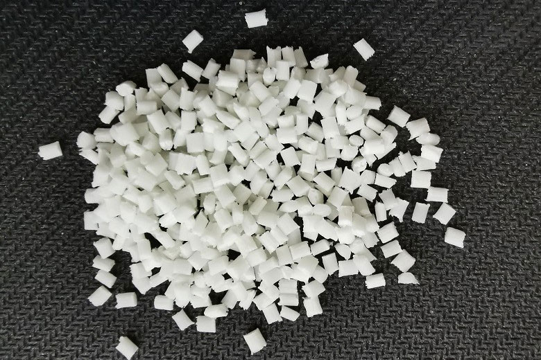 Close-up view of white adipic acid pellets, essential for nylon production.