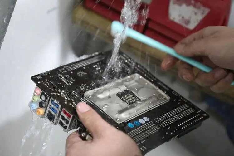 Technician cleaning a computer motherboard with MEK solution for optimal electronic performance.