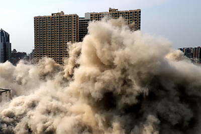 Controlled demolition of a building with a large dust cloud.