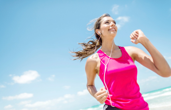 Energetic woman running on the beach, symbolizing enhanced athletic performance from MCT oil supplementation.