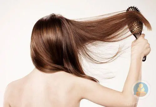 Woman brushing her long, healthy hair, illustrating the use of MCT oil for hair care.