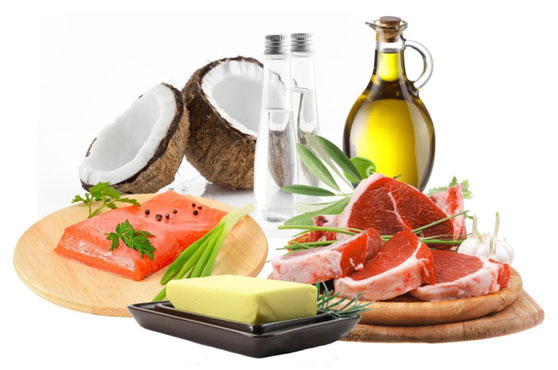 A variety of ketogenic diet foods including salmon, coconut, olive oil, butter, and raw steak garnished with herbs.